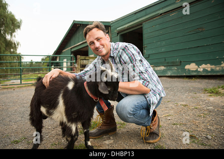 Ein Bio-Bauernhof in den Catskills. Ein Mann mit einer kleinen Ziege auf einem Halfter. Stockfoto