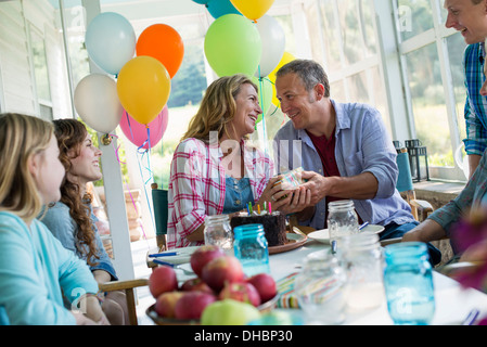 Eine Geburtstagsfeier in einer Landhausküche. Eine Gruppe von Erwachsenen und Kinder versammelten sich um einen Schokoladenkuchen. Stockfoto