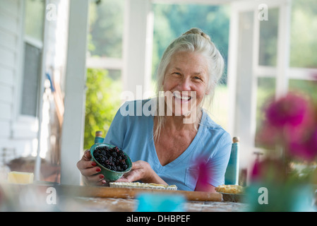 Ein Familienfest in einem Bauernhaus auf dem Land im Staat New York. Eine reife Frau mit Schale mit frischen Brombeeren. Stockfoto