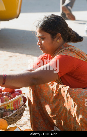 Südindischen Dorf Frau in roten und orangefarbenen Sari mit Heiligen Tilac (Shiva Auge) auf der Stirn mit Obst am Straßenrand Stockfoto