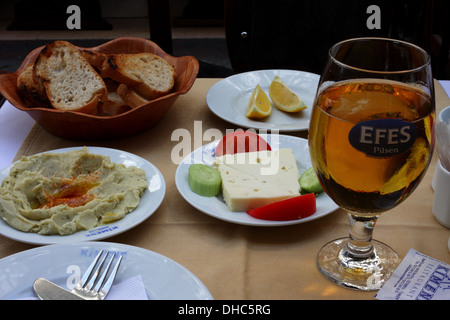 Eine türkische Mahlzeit - Brot, Hummus, Käse, Tomate, Gurke, Zitrone und Efes Bier auf einem Tisch in einem Restaurant in Istanbul Stockfoto