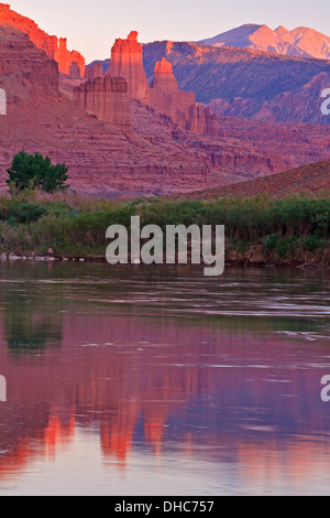 Red Fisher Towers teilweise beleuchtet durch die letzte der Einstellung Sonne und lila Berge spiegeln sich in den Colorado River in der Nähe von Moab, UT Stockfoto