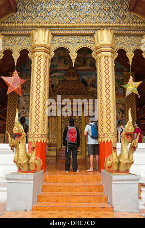 Vertikale Ansicht von Touristen auf der Suche und Fotografieren an der Vorderseite eines buddhistischen Tempels in Wat, die in Luang Prabang. Stockfoto