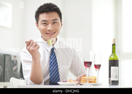 Porträt der Geschäftsmann sitzt am Schreibtisch mit Essen Stockfoto