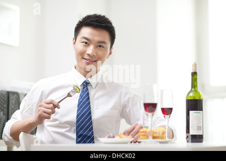 Porträt der Geschäftsmann sitzt am Schreibtisch mit Essen Stockfoto