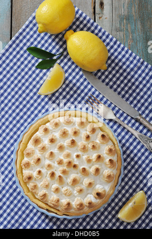 Lemon Meringue Pie mit frischen Zitronen auf karierten Hintergrund Stockfoto