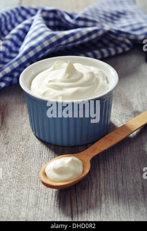 Griechischer Joghurt in eine Keramikschale mit Löffeln auf hölzernen Hintergrund Stockfoto