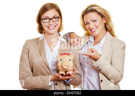 Zwei Unternehmerinnen halten Sparschwein, Lächeln Stockfoto