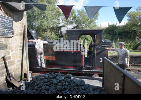 Der Feuerwehrmann der ehemaligen Coal Board Tank Motor Dampf Lok Nr. 3 "Twizell" Tanks mit Wasser füllt, als der Fahrer auf Andrews House Station auf die Tanfield Eisenbahn, die Welten ältesten Eisenbahn - Pferd gezogen, in der Grafschaft Durham anschaut. Stockfoto