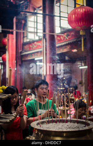 Ein Mann und Frauen Licht Räucherstäbchen und beten während Chinese New Year, Sze Ya Tempel, Chinatown, Kuala Lumpur, Malaysia Stockfoto