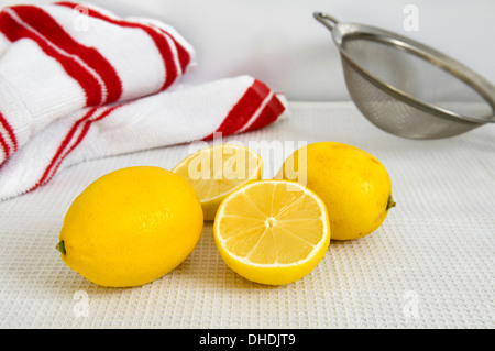 Frische Zitronen auf Arbeitstisch mit Tee Tuch und Sieb im Hintergrund Stockfoto