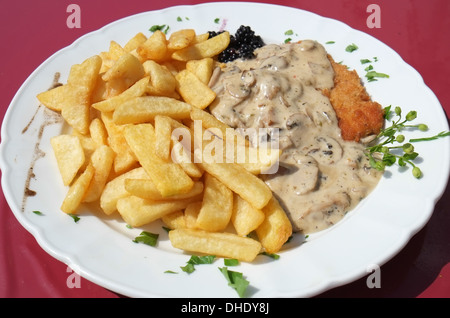 Ein Schnitzel mit einer Pilz-Sahne-Sauce, serviert mit Pommes frites Stockfoto