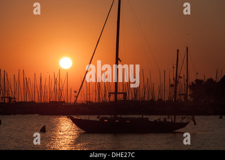 Die aufgehende Sonne dreht den Himmel orange Segelboote und andere Sportboote angedockt im Hafen in Annapolis, Maryland. Stockfoto