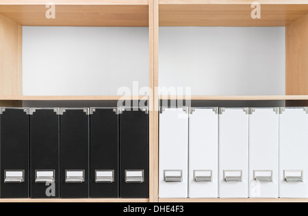 Bücherregal mit schwarzen und weißen Ordner und zwei leere Regale. Stockfoto