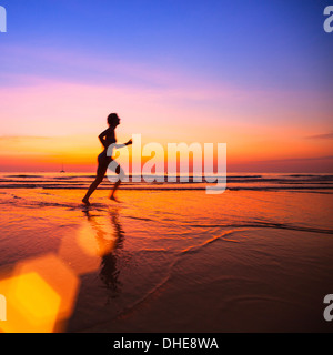 Silhouette der Frau Jogger am Strand bei Sonnenuntergang. Stockfoto