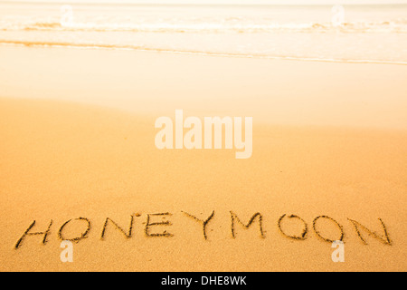 Flitterwochen, Text, der im Sand am Strand, mit einer sanften Welle. Stockfoto