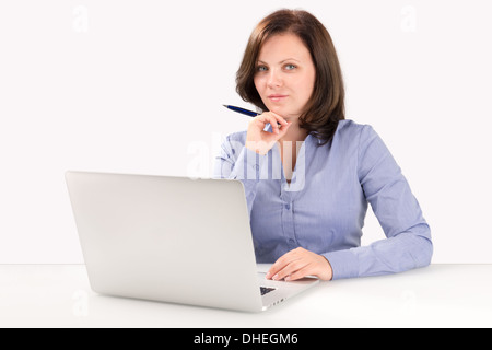 Geschäftsfrau vor einem modernen Laptop sitzt und schaut in die Kamera, Business-Konzept Stockfoto