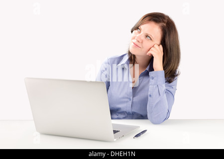 Business-Frau sitzt vor einem Laptop stützte sich auf einen Arm und sah in der oberen Ecke des Bildschirms Stockfoto