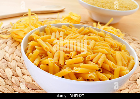 einige verschiedene Teigwaren wie Penne Rigate, Tagliatelle und Suppeneinlage, auf einem Tisch Stockfoto