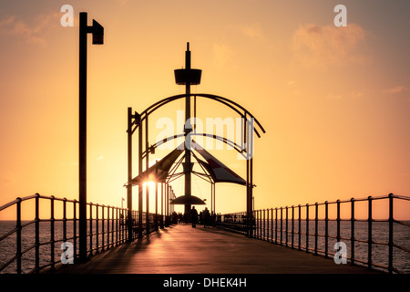 Sonnenuntergang auf einer der wunderschönen Brighton Pier in Australien, ein an der Küste mit kristallklarem Wasser und einem unberührten Sandstrand Stockfoto