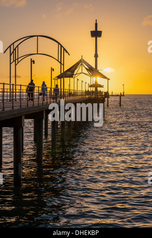 Sonnenuntergang auf einer der wunderschönen Brighton Pier in Australien, ein an der Küste mit kristallklarem Wasser und einem unberührten Sandstrand Stockfoto