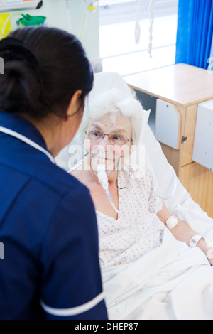 Eine philippinische Krankenschwester hilft eine ältere Frau im Bett UK Stockfoto