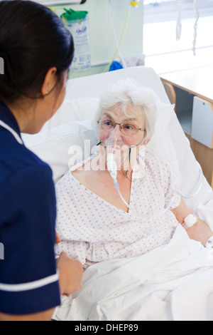 Eine philippinische Krankenschwester hilft eine ältere Frau im Bett UK Stockfoto