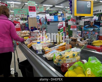 Frau Rückseite des Käufers an der Kasse gefüllt mit Lebensmitteln Lebensmittel in Kunststoffverpackungen im Co-Op Supermarkt in Wales Großbritannien KATHY DEWITT Stockfoto