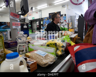 Ein männlicher Arbeiter, der an der Kasse arbeitet, füllte Lebensmittel, Milch, Plastikverpackungen im Co-Op Supermarkt Wales UK KATHY DEWITT Stockfoto