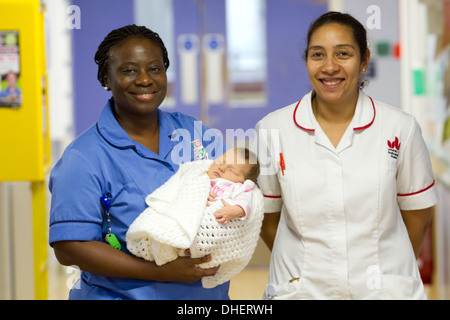 Eine Hebamme hält ein neues Baby geboren mit einer Studentin Hebamme suchen auf UK Stockfoto