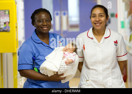 Eine Hebamme hält ein neues Baby geboren mit einer Studentin Hebamme suchen auf UK Stockfoto