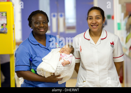 Eine Hebamme hält ein neues Baby geboren mit einer Studentin Hebamme suchen auf UK Stockfoto