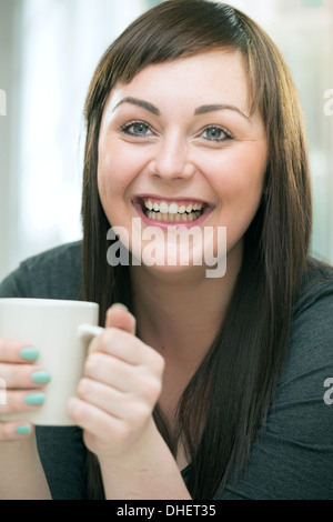 Junge Frau mit Heißgetränk, Lächeln Stockfoto