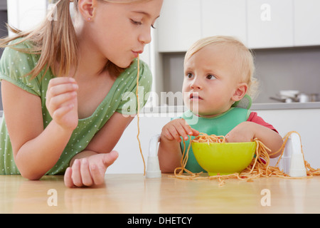 Mädchen und Kleinkind spielt mit spaghetti Stockfoto
