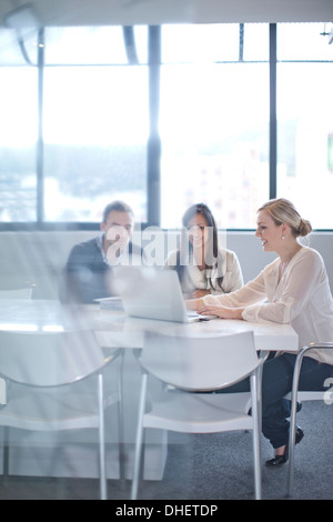 Geschäftsleute sitzen am Konferenztisch Blick auf laptop Stockfoto