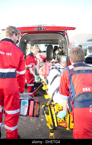 Heben Frau auf Bahre in Krankenwagen Sanitäter Stockfoto