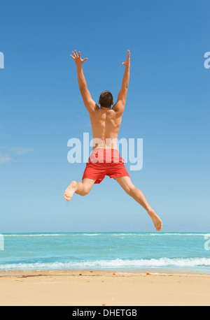 Mann springt am Strand Stockfoto
