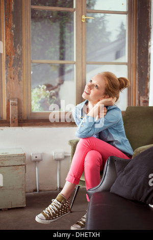 Junge Frau sitzt mit gekreuzten Beinen Stockfoto