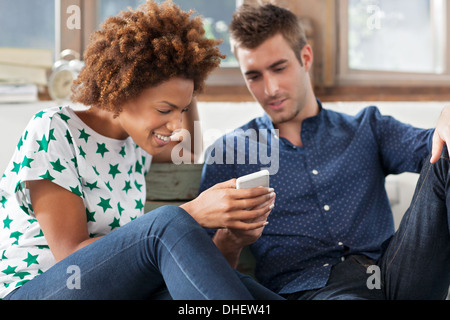 Frau mit Smartphone, Mann beobachtet Stockfoto