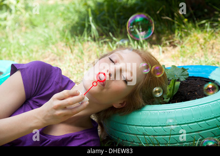 Frau liegend auf Reifen Seifenblasen Stockfoto
