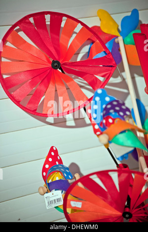 Kinder bunte bunte Meer Spielzeug Windmühlen gegen helle weiße Holzwand Stockfoto