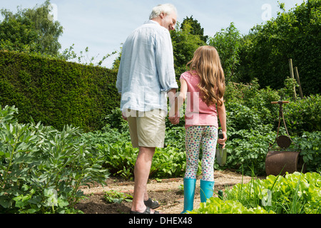 Großvater und Enkelin Hand in Hand im Garten Stockfoto