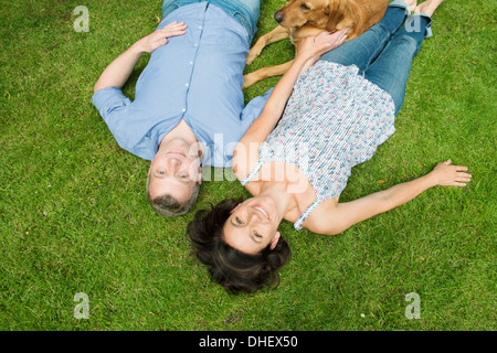 Porträt des reifes Paar liegen auf dem Rasen mit Hund Stockfoto