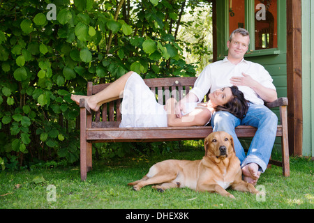 Porträt von älteres Paar auf Gartenbank mit Hund Stockfoto