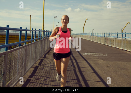 Junge weibliche Jogger laufen über Brücke Stockfoto