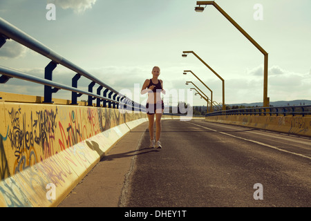 Junge weibliche Jogger läuft auf Brücke Stockfoto