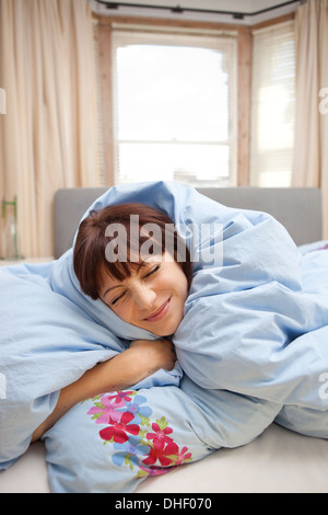 Junge Frau in Bettdecke gewickelt Stockfoto