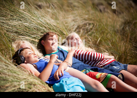 Vier Freunde, die Entspannung in Dünen, Wales, UK Stockfoto