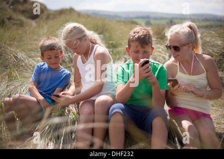 Vier Freunde, die Entspannung in Dünen, Wales, UK Stockfoto