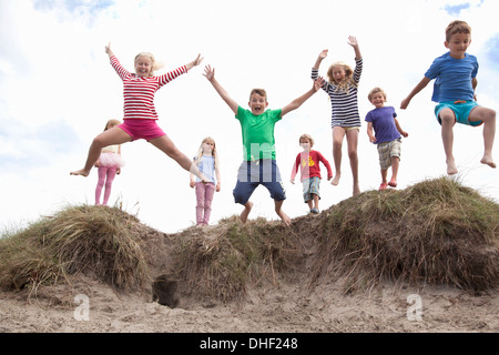 Gruppe von Kindern abspringen Sanddünen, Wales, UK Stockfoto